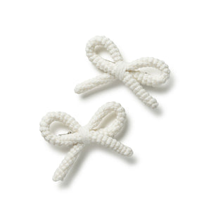 Two white bow-shaped hair clips on a white background