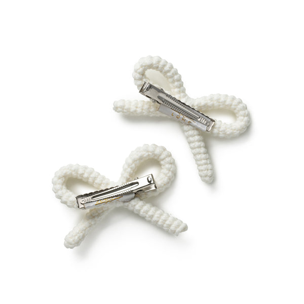 Two white hair clips with bow designs on a white background
