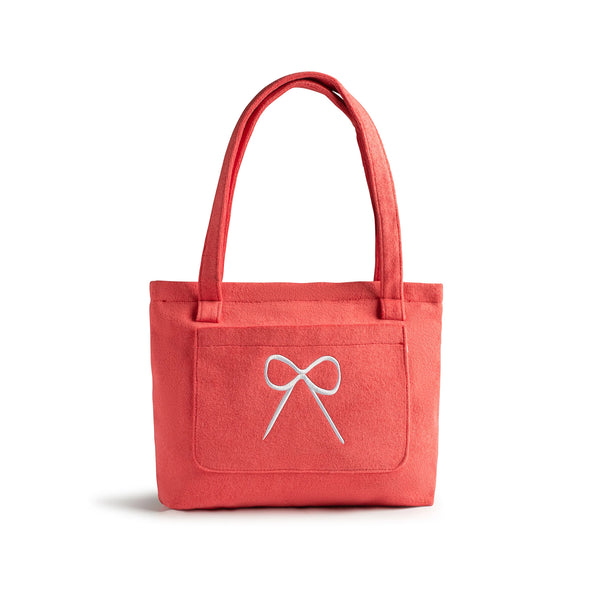 pink tote bag with a white bow design  of haloluxe branding in centre