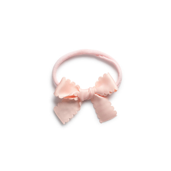 A pink satin baby bow headband with scalloped edges.