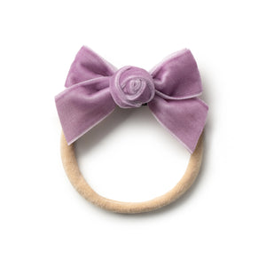 A lavender velvet baby headband with a rosette detail on top.