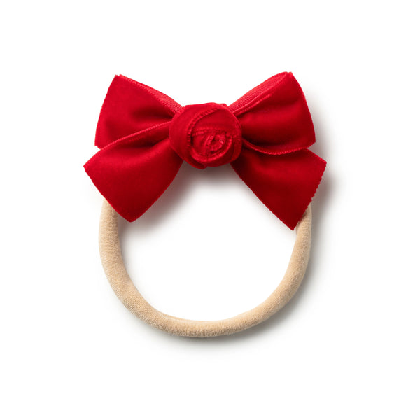 A red velvet baby headband with a rosette detail on the top.