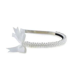 A white headband featuring a double-strand pearl design with a grosgrain bow on the side.