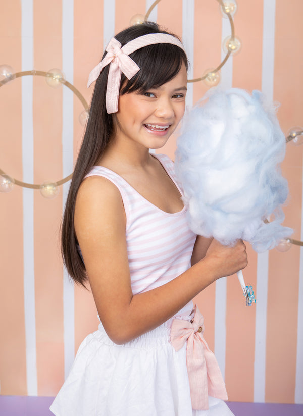 A teenage girl wearing eyelet side bow headband in cream by Halo Luxe