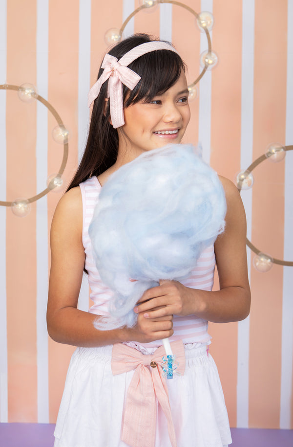 A teenage girl wearing eyelet side bow headband in cream by Halo Luxe