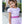 Load image into Gallery viewer, Young girl in a lavender dress with a pink belt and lavender rosette velvet headband, standing outdoors.
