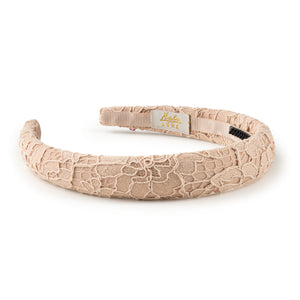 Beige lace headband with a visible brand label on a white background