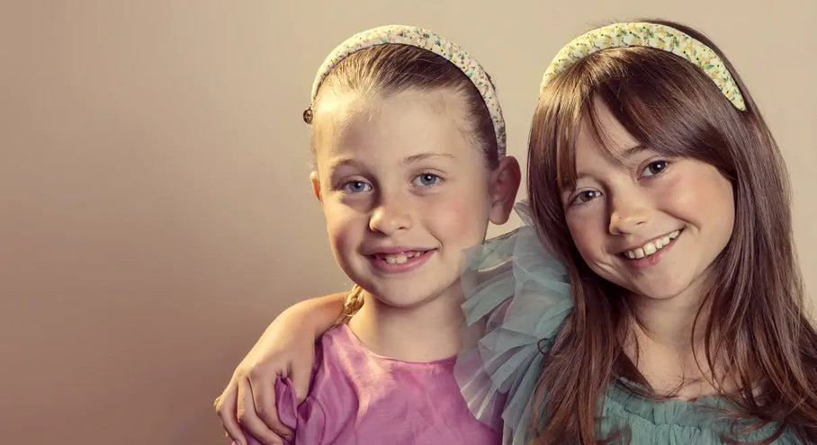 Two young girls wearing headbands in pastel outfits