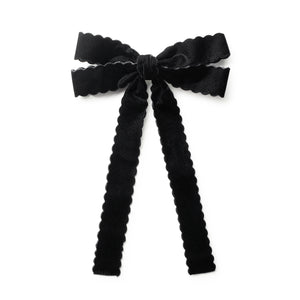 Black bow hair clip with ruffled edges on a white background
