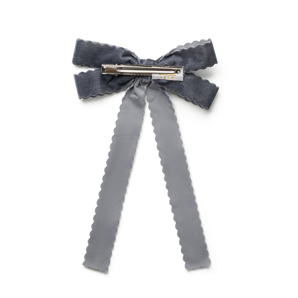 Gray bow hair clip with ruffled edges on a white background