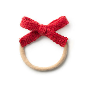 Baby headband featuring a soft red knitted bow attached to a neutral elastic band.