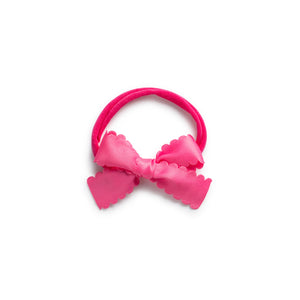 A hot pink satin baby bow headband with scalloped edges.