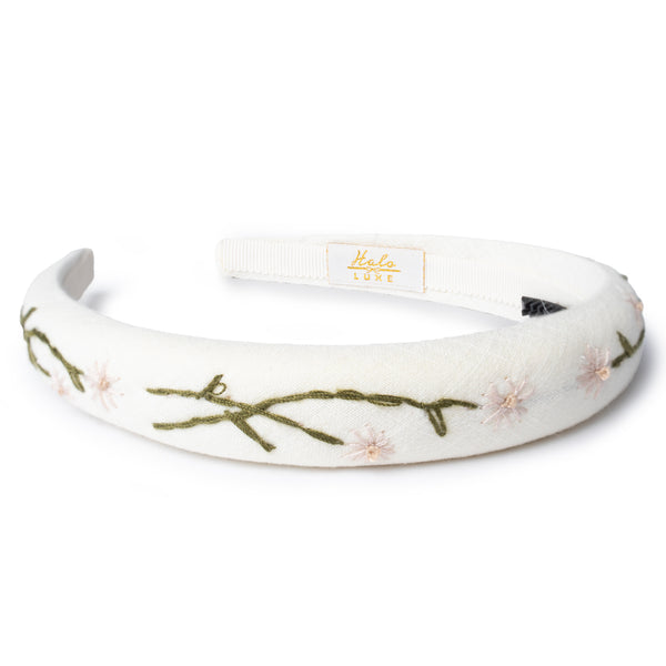 ivory headband with floral embroidery on a white background