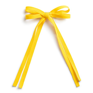 A yellow bow hair clip with a long tail on a white background