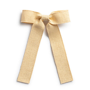 A buttermilk colored linen long tail hair clip with a bow knot, fastened with an alligator clip.