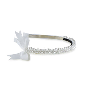 A white headband featuring a double-strand pearl design with a grosgrain bow on the side.