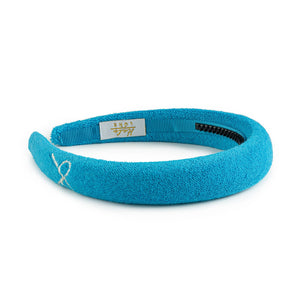 A teal colored Halo Luxe Terry cloth Headband for girls with the brand's embroidery on the front.